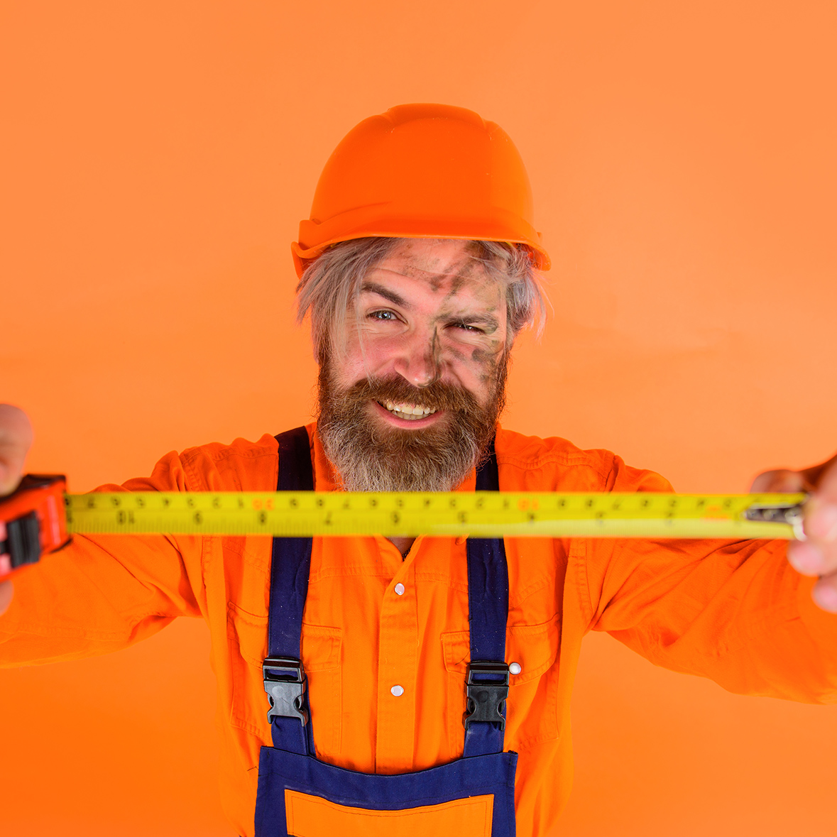 Builder with measure tape. Selective focus. Measuring device. Construction worker. Worker use tape measure. Builder equipment. Bearded builder in protective helmet. Repair tools